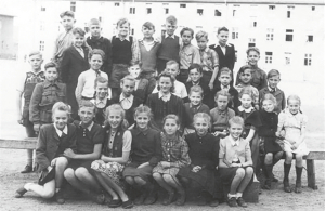 Kara bēgļi. Lībekas latviešu pamatskolas 5. klases kopbilde 1948. gada vasaras beigās. Vaira pirmajā rindā pirmā no labās, fonā — bēgļu kazarmas. Karš pilnīgi mainīja ģimenes likteni, liekot doties bēgļu gaitās un nesot traģisku zaudējumu — tikai dažas nedēļas pēc Rīgas pamešanas 1945. gada janvārī briesmīgajos apstākļos Vācijā saslima un nomira Vairas mazā māsa Mārīte. Foto no privātā arhīva