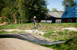 BMX trase tapusi pirms diviem gadiem. Tās izveidi atbalstīja vietējie uzņēmēji un Teterevu fonds. Šogad trase bija iekļauta Vivus.lv MTB maratona posmā. Ikdienā tajā trenējas bērni. Uz galda pie trases ir ķiveres, ko nolicis Sandris Janušs, trases autors, jo vecāki bērniem nez kāpēc ķiveres nepērkot. Foto — Ieva Salmane