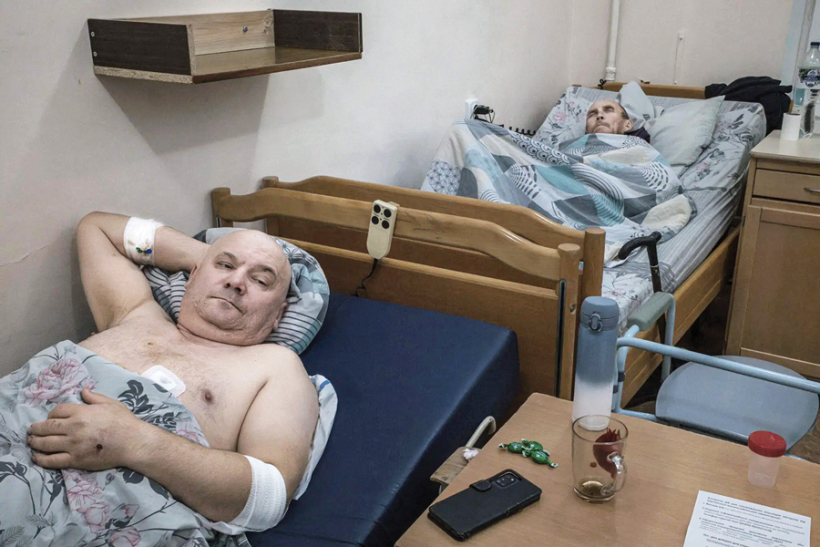 Autostāvvietas apsargs Volodimirs Oleiničuks (priekšplānā), dzirdot dronu, paslēpās zem sarga būdiņas, taču viņam trāpīja vairākas spridzekļa šķembas