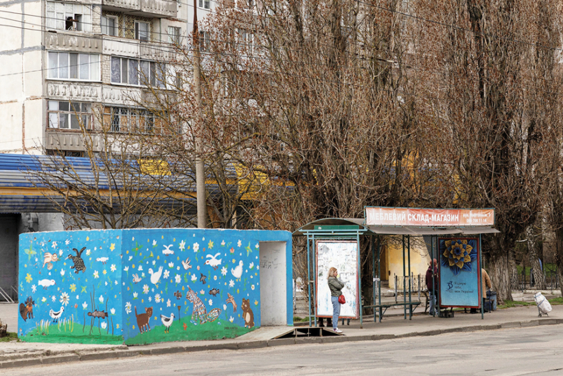 Trolejbusu pietura Hersonā, kurai blakus novietota betona patvertne, lai cilvēki varētu paslēpties no droniem