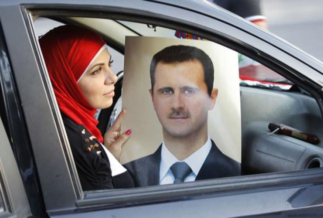 Sīriešu sieviete automašīnā tur Bašara al Asada portretu. Foto: AFP/LETA
