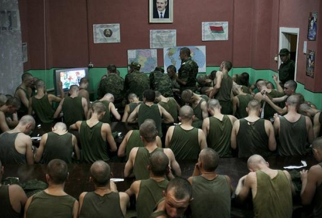 Fotogrāfijā, kas konkursā ieguva galveno balvu, redzami baltkrievu karavīri, skatoties vakara ziņu raidījumu. Tas ir obligāts pasākums visiem iesauktajiem. Šis ideoloģiskās audzināšanas paņēmiens Baltkrievijas armijā saglabājies vēl no padomju laikiem. Baltkrievija, Minskas apgabals, Borisova, 60.sakaru pulks 2010.gada 6.augustā. Foto autors – Sergejs Gudiļins