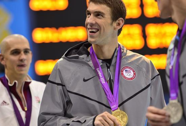 ASV peldētājs Maikls Feplss ar Londonā ceturtdien izcīnīto zelta medaļu 200 metru peldējumā. Foto: AFP/LETA