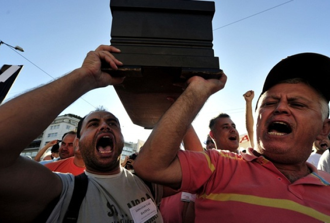 Grieķu taksometru šoferi protestē pret finansējuma samazinājumu. Atribūtika pazīstama arī Latvijā - zārks. Foto: AFP/LETA