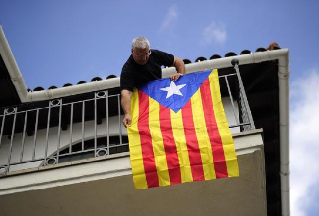 Kāds vīrs izkar Katalonijas karogu. Foto: AFP/LETA