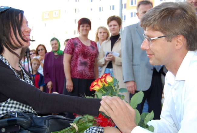 Rīgas mērs Nils Ušakovs (pa labi) jaunas dzīvojamās mājas atklāšanā saņem ziedus no pateicīgajiem īrniekiem. Foto: Inga Nestere, F64