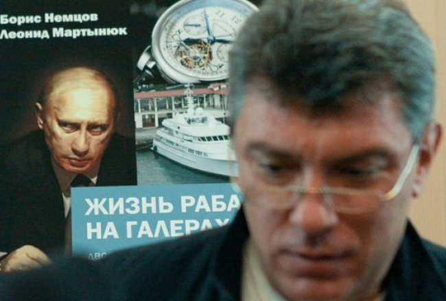 Opozīcijas politiķis Boriss Ņemcovs pozē savas un Leonīda Martiņuka sarakstītās grāmatas par prezidenta Putina privilēģijām "Verga dzīve galerās" vāka fona. Foto: ITAR-TASS/LETA