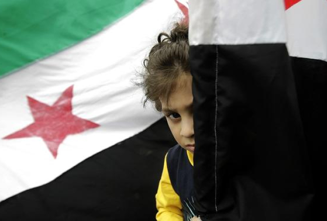 Bērns pie Sīrijas valsts karoga. Foto: AFP/LETA