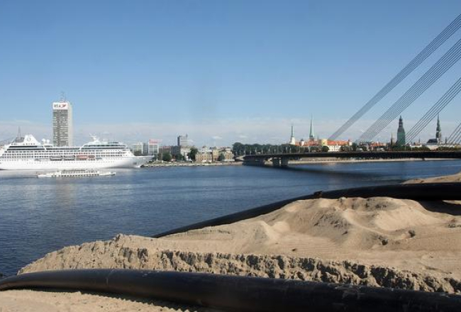 Kruīza kuģis piestātnē Daugavas labajā krastā un smilšu kalns pretējā krastā. Foto: Edijs Pālens, LETA