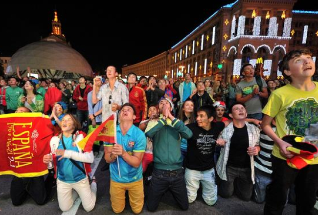Spānijas futbola fani Kijevas centrā vēro pusfināla spēli. Foto: AFP/LETA