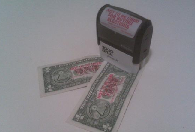 Pirms Saeimas vēlēšanām 2006.gadā pozitīvisma kampaņu laikā Tautas partija sludināja, ka ASV nav priekšvēlēšanu tēriņu ierobežojumi un ar demokrātiju tur viss ir kārtībā. Nu daudzi pilsoņi ASV tā neuzskata un savu attieksmi pauž, apzīmogojot dolārus ar saukļiem “Not to be used for buying elections” (Neizmantot vēlēšanu pirkšanā – angļu val.). Autora foto