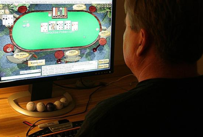 Vīrietis spēlē pokeru ar savu datoru. Foto: AFP/LETA