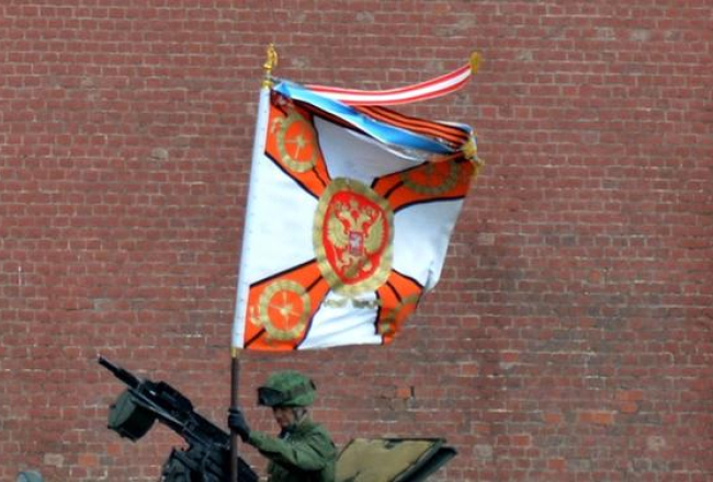 Krievijas armijas karavīrs uz bruņutransportiera nostiprina Svētā Georga karogu, gatavojoties 9.maija parādei Maskavas Sarkanajā laukumā. Foto: AFP/LETA