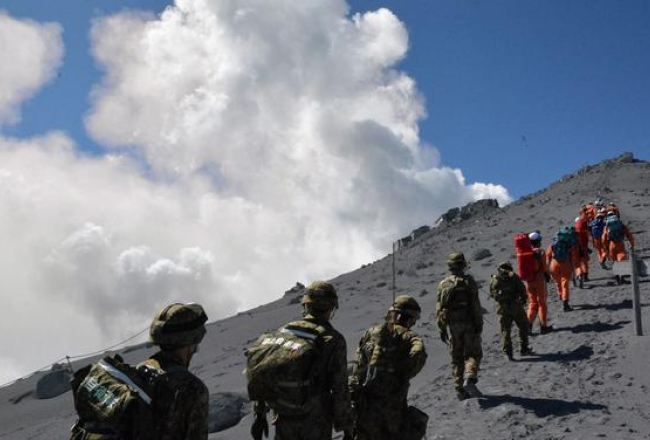 Glābēji un karavīri steidzas palīgā Ontakes vulkāna virsotnē palikušajiem tūristiem. Foto: AFP/LETA