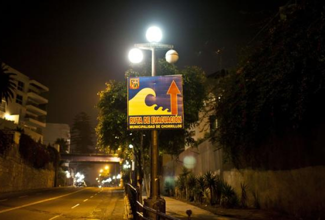 Peru, Lima. Ielā uzstādītā zīme rāda evakuācijas virzienu cunami gadījumā. Foto: AFP/LETA