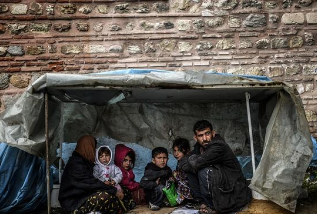 Sīriešu bēgļu ģimene apmetusies Stambulā pie kādas mūra sienas. Foto: AFP/LETA