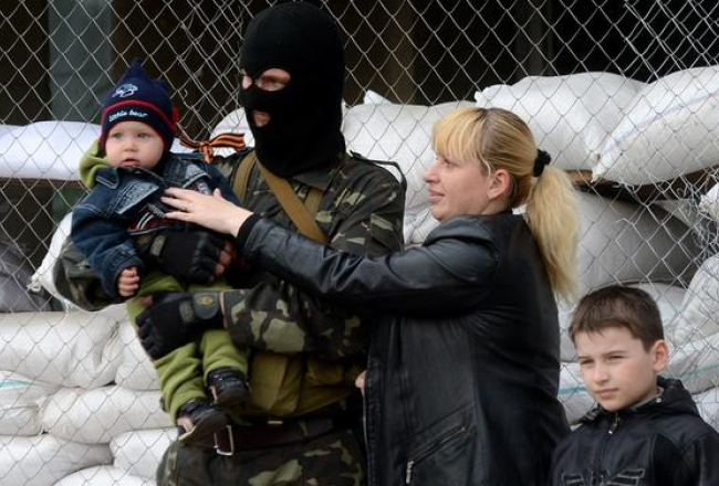 Lieldienu ģimenes foto Ukrainas promaskavas separātistu ieņemtajā Slavjanskā. Māte bērnus liek fotografēt kopā ar maskotiem separātistiem pie barikādēm. Foto: AFP/LETA