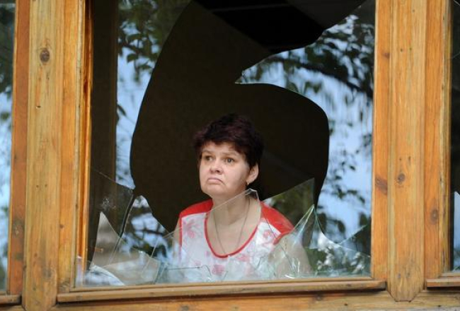 Sieviete Slovjanskā skatās caur sašautu logu. Foto: EPA/LETA
