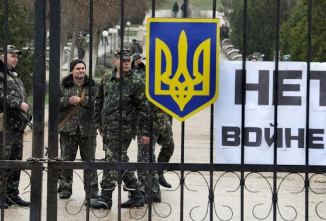 Ukrainas karavīri Belbekas bāzē pie Sevastopoles. Pie vārtiem plakāts ar uzrakstu: "Nē karam!". Foto: AFP/LETA