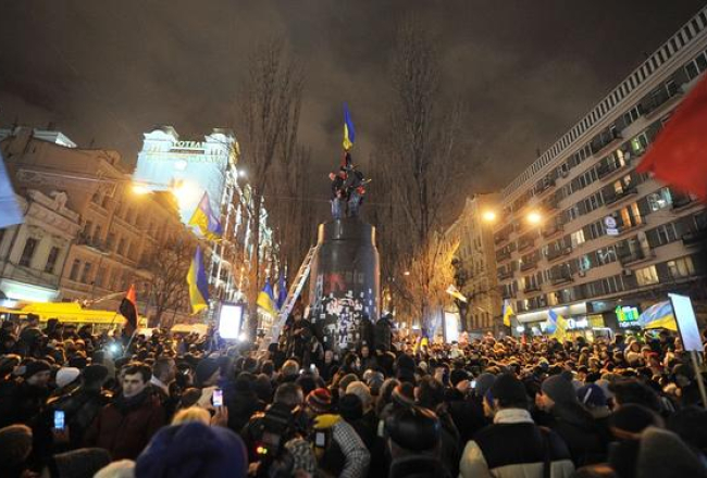 Protestētāji Ļeņina pieminekļa vietā uzvilkuši Ukrainas karogu. Foto: AFP/LETA