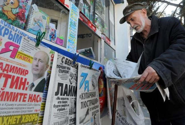 Krimā vīrs pie avīžu kioska lasa Krievijas laikrakstus. Foto: AFP/LETA