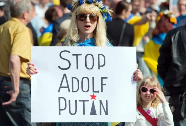 Ukrainas neatkarību atbalstoša demonstrante Vācijas pilsētā Frankfurtē pie Mainas rokās tur plakātu ar uzrakstu: "Stop Adolf Putin". Foto: EPA/LETA