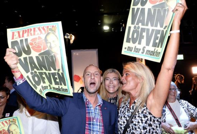 Zviedrijas sociāldemokrātu atbalstītāji līksmo par uzvaru vēlēšanās, rādot "dzeltenās" vakara avīzes "Expressen" vāku, kurā pausts atbalsts Stēfanam Levēnam. Foto: AFP/LETA