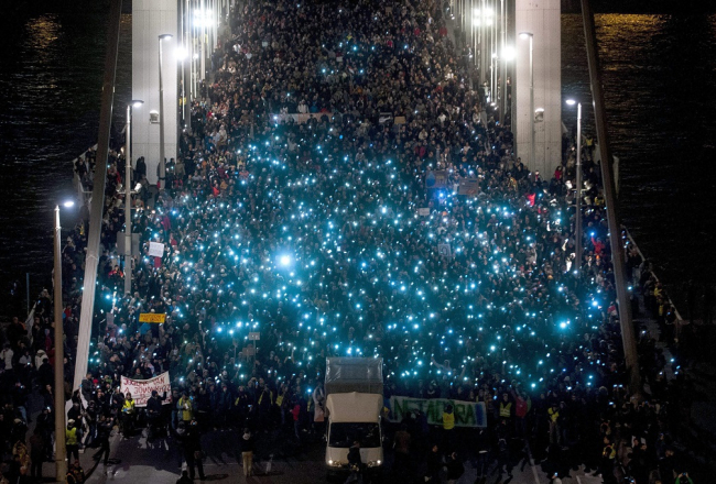 Protestētāji pret interneta nodokli Budapeštā uz Elizabetes tilta pār Donavu spīdina mobilo telefonu gaismiņas. Foto: EPA/LETA