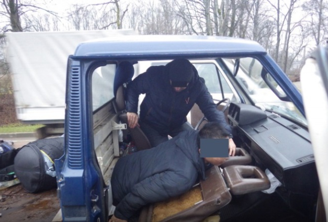 Nelegālie imigranti tiek izvilkti no slēptuves automašīnas grīdā. Foto: Valsts robežsardze/Delfi