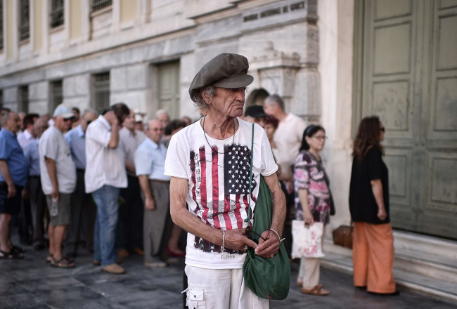 Cilvēki gaida Atēnās, kad atvērsies Grieķijas Nacionālās bankas durvis. Foto: AFP/LETA