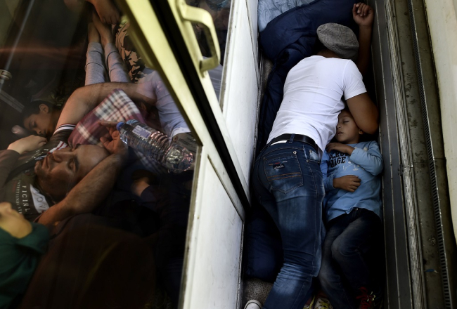 Sīrijas bēgļi guļ vilcienā ceļā no Maķedonijas. Foto: AFP/LETA