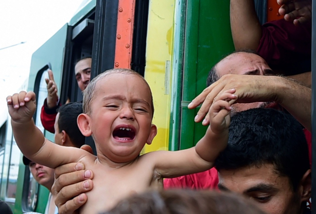 Patvēruma meklētāju bērns tiek iecelts vilcienā Budapeštas dzelzceļa stacijā. Foto: AFP/LETA