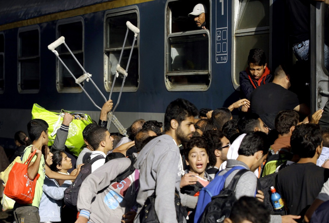 Pēc varas iestāžu atļaujas bēgļi traucas ieņemt vietas vilcienos. Foto: AFP/LETA