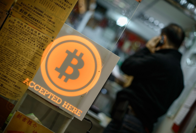Virtuālā valūta "Bitcoin" - ar to var norēķināties te, rakstīts kādā Honkongas iestādē. Foto: AFP/LETA