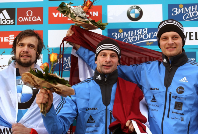 Uz pjedestāla Martins Dukurs (centrā), Tomass Dukurs un krievu sportists Aleksandrs Tretjakovs. Foto: EPA/LETA