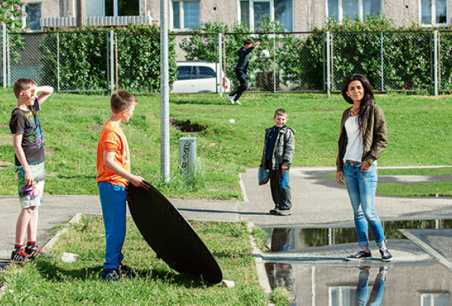 Bolderājas puikas ielenkuši Aminatu fotografēšanas laikā un pat palīdz izgaismot dziedātājas seju.