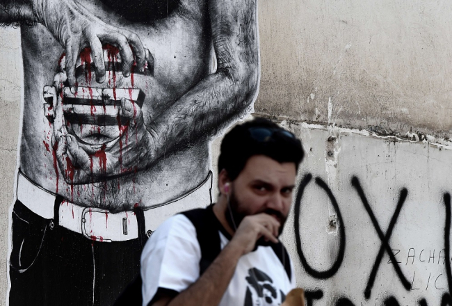 Attēlā redzamais grafiti Atēnās var izrādīties grieķiem atbilstošs - būs krietni jāsavelk jostas. Foto: AFP/LETA
