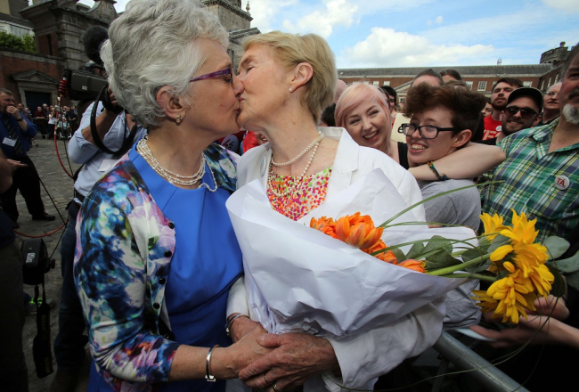 Īrijas senatore Katerīna Zappone (pa kreisi) noskūpsta savu partneri Annu Luīzi Džiliganu, demonstrējot atbalstu viendzimuma laulību legalizācijai. Foto: AFP/LETA