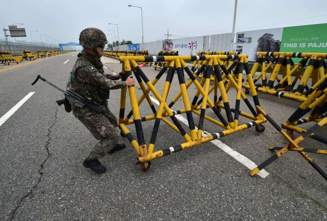 Dienvidkorejas kareivis uzstāda barjeru pie militārā kontrolpunkta uz ceļa, kas ved uz Ziemeļkoreju. Foto: AFP-LETA