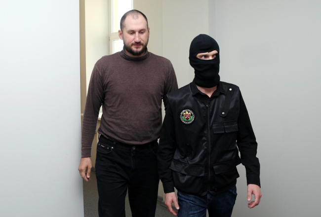 Viens no aizturētajiem Krievijas pilsoņiem Aleksandrs Kurkins, kurš nelikumīgi bija iekļuvis Ādažu militārajā bāzē un pie kura atrastas skrejlapas angļu valodā, tiek konvojēts uz Rīgas pilsētas Vidzemes priekšpilsētas tiesas sēdi, kurā lems par drošibas līdzekļa piemērošanu. Foto: Ieva Čīka, LETA