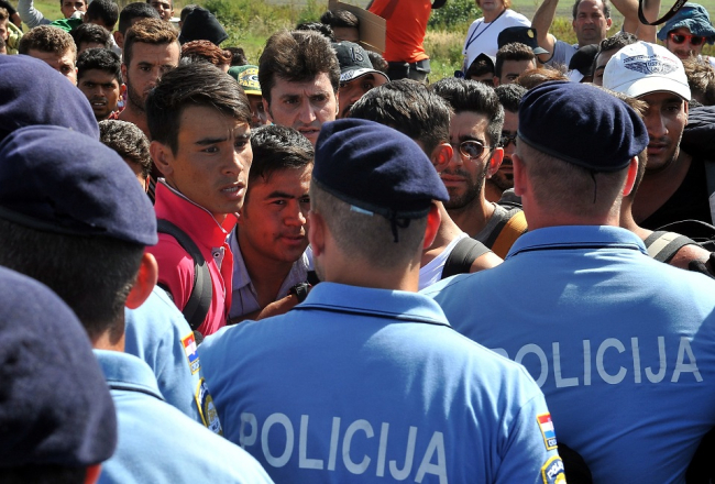 Policisti Horvātijas austrumos pie Tovarnikas apturējuši migrantus un bēgļus, kad tie pameta dzelzceļa staciju, lai dotos uz Zagrebu. Foto: EPA/LETA
