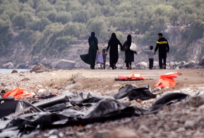Migrantu ģimene Lesbos salā Grieķijā pēc ierašanās no Turcijas puses aiz sevis atstāj pamestas glābšanas vestes un dodas tālāk. Foto: AFP/LETA