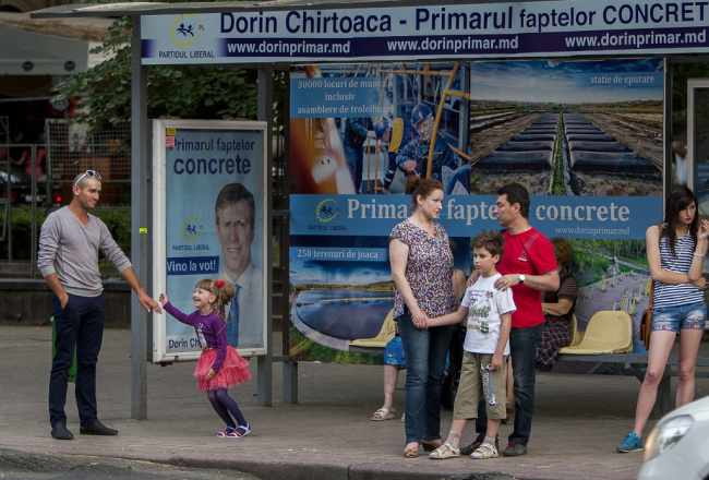 Pieturvieta Kišiņevā ar Liberālās partijas pārstāvja un nu jau vēlēšanu uzvarētāja Dorina Kirtoakes reklāmu. Foto: EPA/LETA
