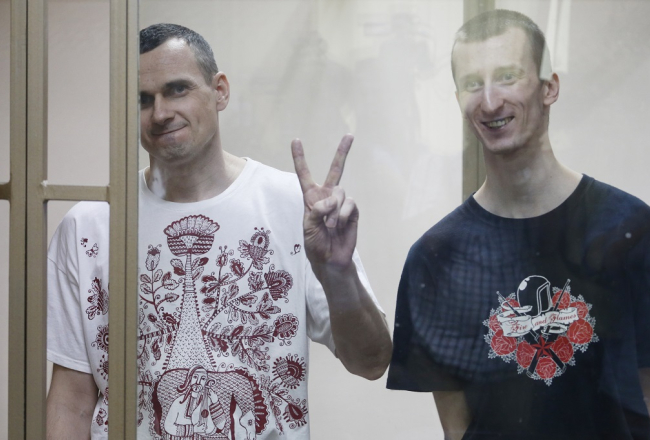Oļegs Sencovs (no kreisās) Rostovas tiesas zālē rāda uzvaras zīmi sprieduma nolasīšanas laikā. Viņam līdzās - Aleksandrs Koļčenko, kuram tiesa piesprieda 10 gadus cietumā. Foto: ITAR-TASS/LETA