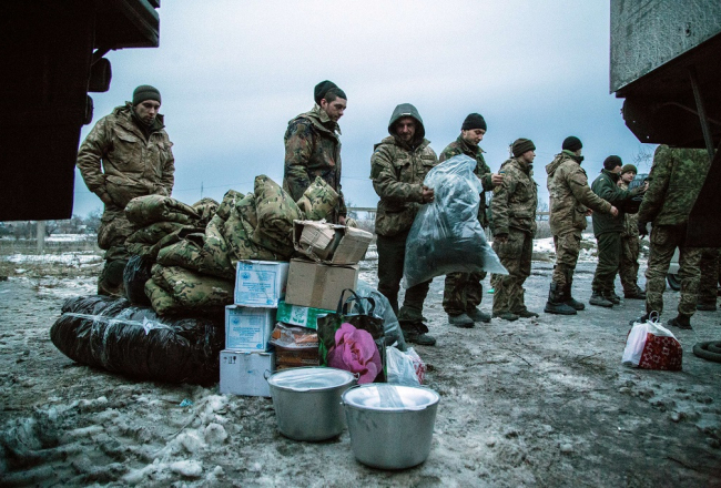 Ukrainas karavīri pie Avdejevkas saņem brīvprātīgo sarūpētos apģērbus un citas nepieciešamas lietas. Foto: AFP/LETA