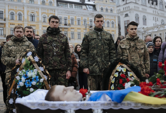 Vienlaikus ar sarunu noslēgumu Minskā ceturtdien Kijevas centrā pie Svētās Sofijas katedrāles notika atvadīšanās no Austrumukrainā nogalinātā Ukrainas armijas brīvprātīgā un Krievijas pilsoņa Kirila Heinza (28). Foto: EPA/LETA