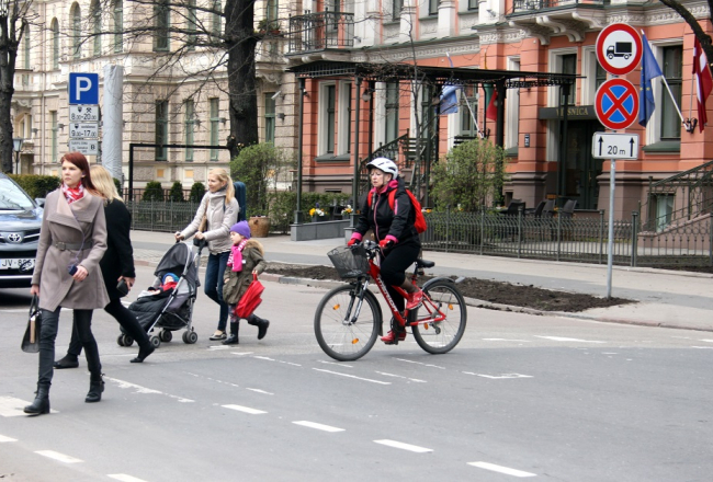 Gājēji un velosipēdists ielā. Foto: Rebeka Žeire, LETA