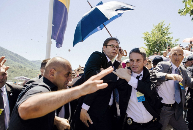 Serbijas premjerministrs Aleksandrs Vučičs (centrā) tiek apmētāts ar akmeņiem. Foto: AFP/LETA