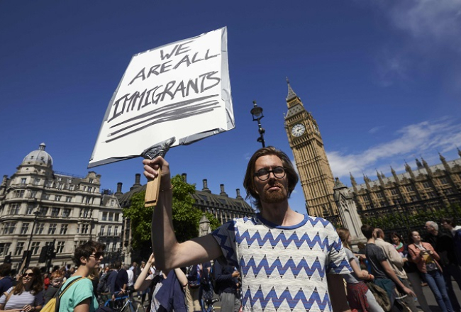 Protesta akcijā Londonā vīrietis tur plakātu ar uzrakstu: "Mēs visi esam imigranti." Foto: AFP/LETA