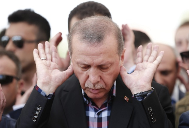 Turcijas prezidents Redžeps Tajips Erdogans lūdzas kapsētā pie militārā apvērsuma mēģinājuma laikā bojāgājušo zārkiem Stambulā. Foto: EPA/LETA